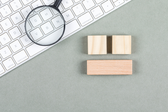 Search concept with magnifier, wooden blocks, keyboard on gray background top view. horizontal image