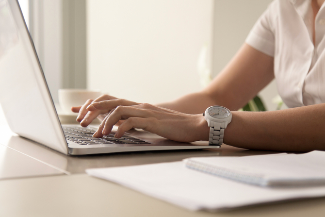 Close up image of womans hands typing on laptop at workplace. Businesswoman with white wristwatch on hand working on computer in office. Female office worker, programmer, entrepreneur searching online