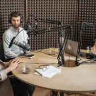 Gravação de podcast empresarial com três profissionais discutindo estratégias de marketing digital em estúdio acústico